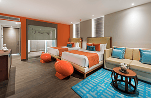 Elegant Nest Suite featuring two queen-sized beds, modern decor, and vibrant accents for a comfortable stay. Perfect for relaxation and enjoying the Husna experience in a stylish, inviting environment.