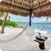 Relaxing beach lounge with white sunbeds and thatched umbrellas on a sandy shore, offering a tranquil seaside retreat.