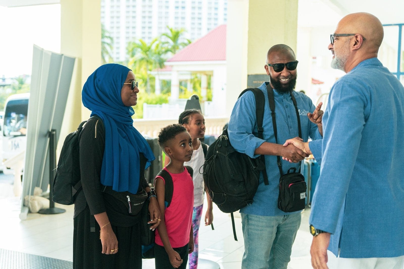 Diverse group of travelers greeting each other warmly at the airport terminal.