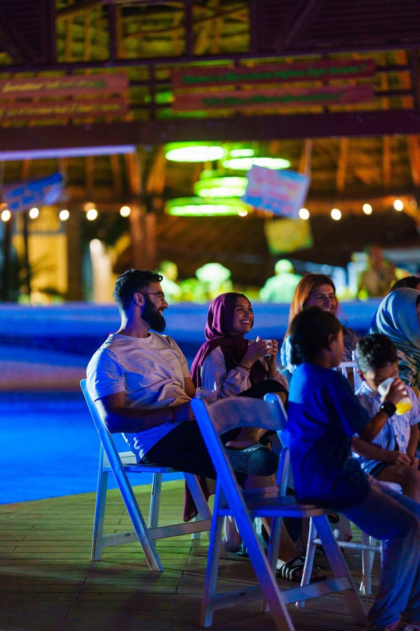 Group of diverse people enjoying a live outdoor event at Beach & Beyond Signature, with vibrant lighting and a relaxed atmosphere.