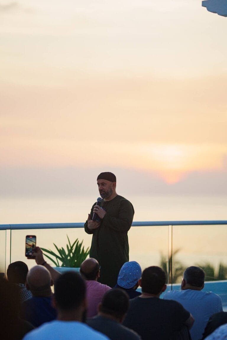 Sunset speaker event at Beach & Beyond, Husna's signature experience, featuring a speaker addressing an audience with the ocean and sunset in the background, creating a serene and inspiring atmosphere.