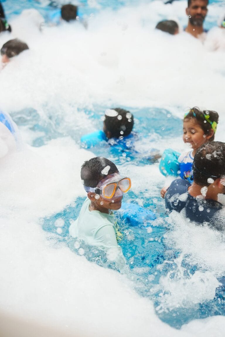 Children enjoying a fun-filled day at the beach with playful waves and clear blue water.